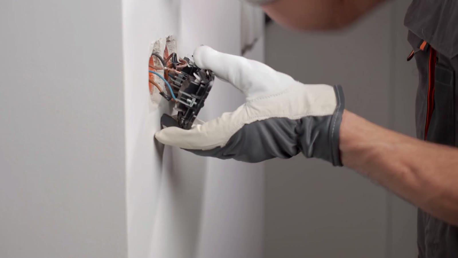 Electrician wiring a switch box into a finished wall